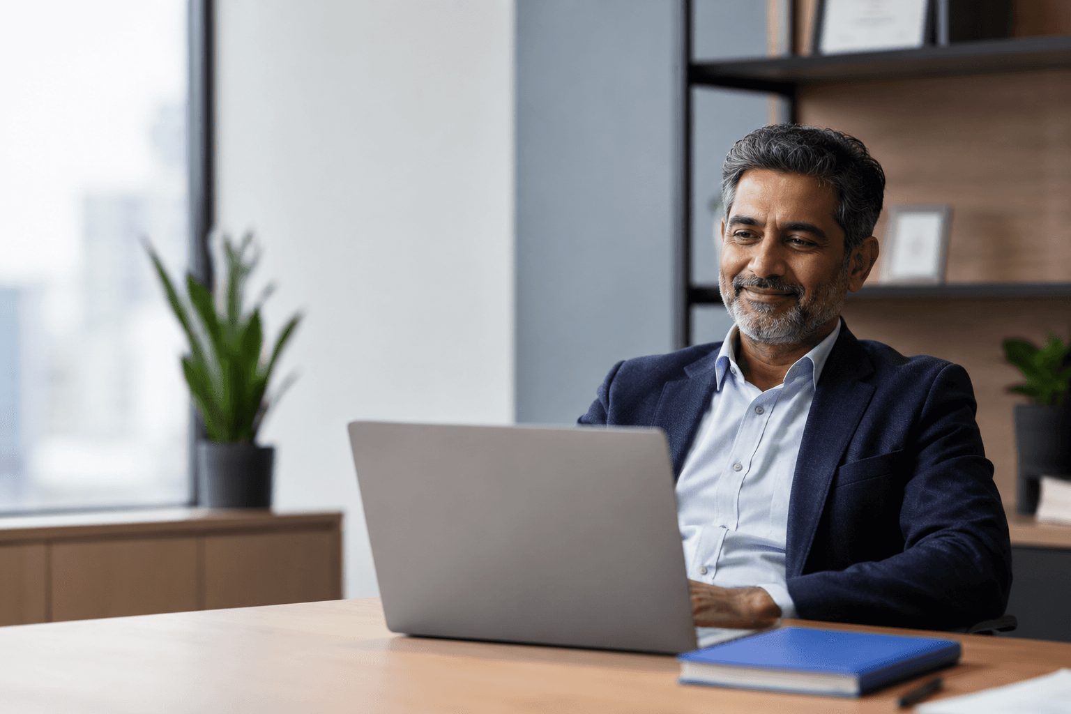 A finance leader leaning back at his desk with a relaxed expression, at ease at his laptop.